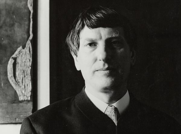 Schwarz-weiß Fotografie im Querformat von Gerhard Altenbourg, im Hintergrund sein Werke zu erahnuen, Schlaglicht von links.