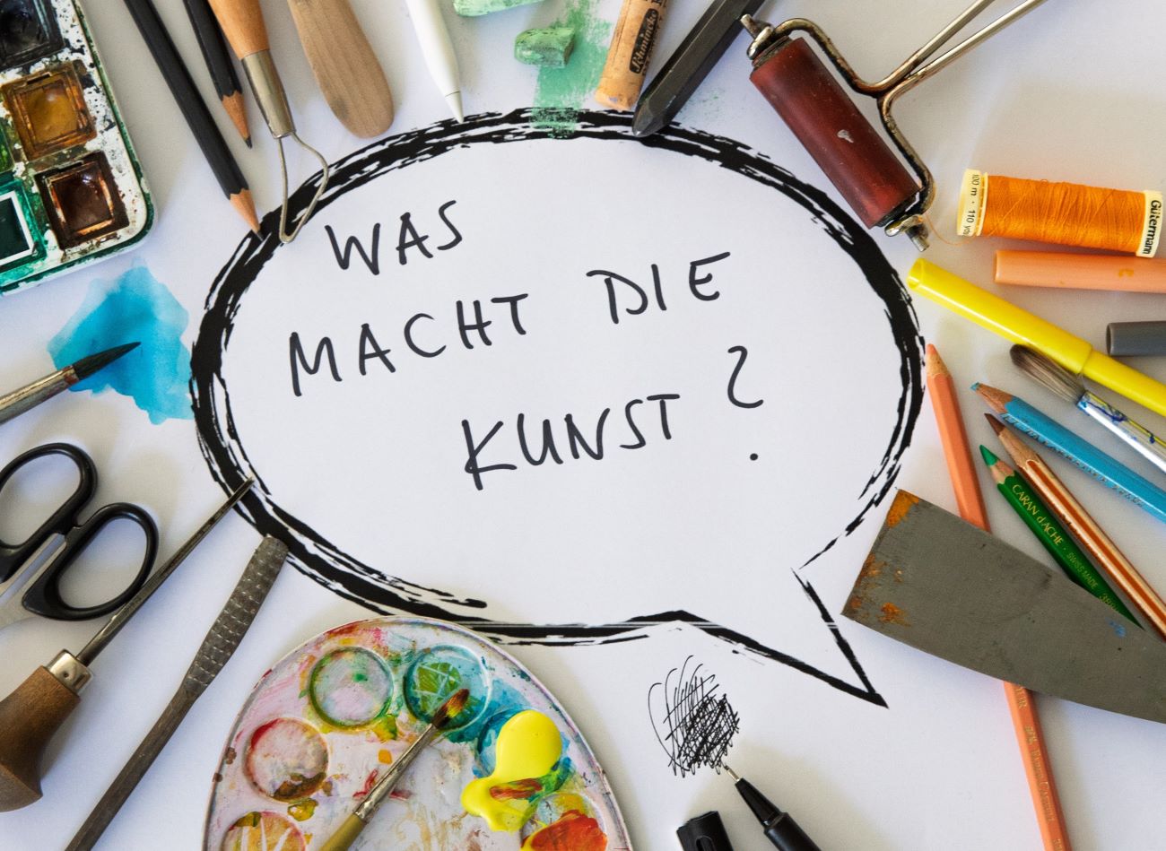 Symbolbild für Arbeiten im studio mit Bastel- und Gestaltungsutensilien und dem Schriftzug "Was macht die Kunst?" in einer Sprechblase